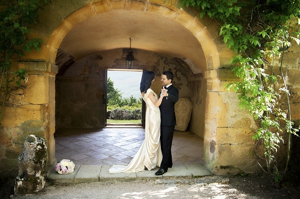 Bride and groom under arch at Ch teau de Bagnols in France