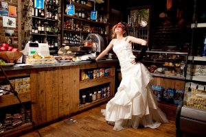 Picture of a bride leaning on the counter of an Italian Deli by Sean Casey Photography