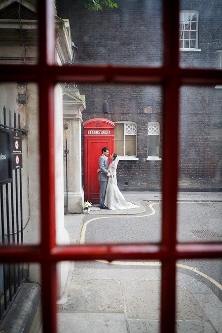 Bride and groom standing by a red telephone box - Picture by Brett Symes Photography