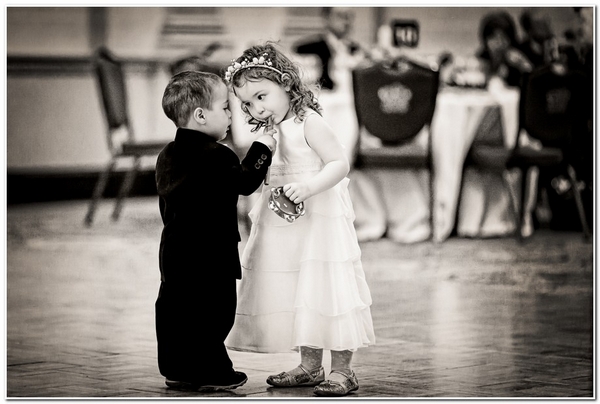 Flower girl blowing whsitle in page boy's hand - Picture by Kevin Mullins Photography