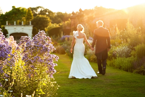 Bride and groom holding hands and walking in hazy sunshine - Picture by Zen Photographic